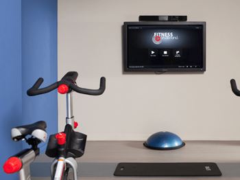 A fitness program is displayed on a television above a stationary exercise bike at Skye at Belltown Apartments, Washington